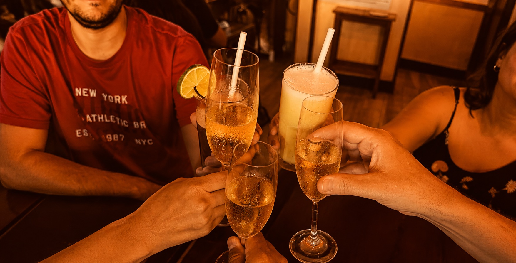 Duas pessoas brindando com drinques em uma mesa de bar